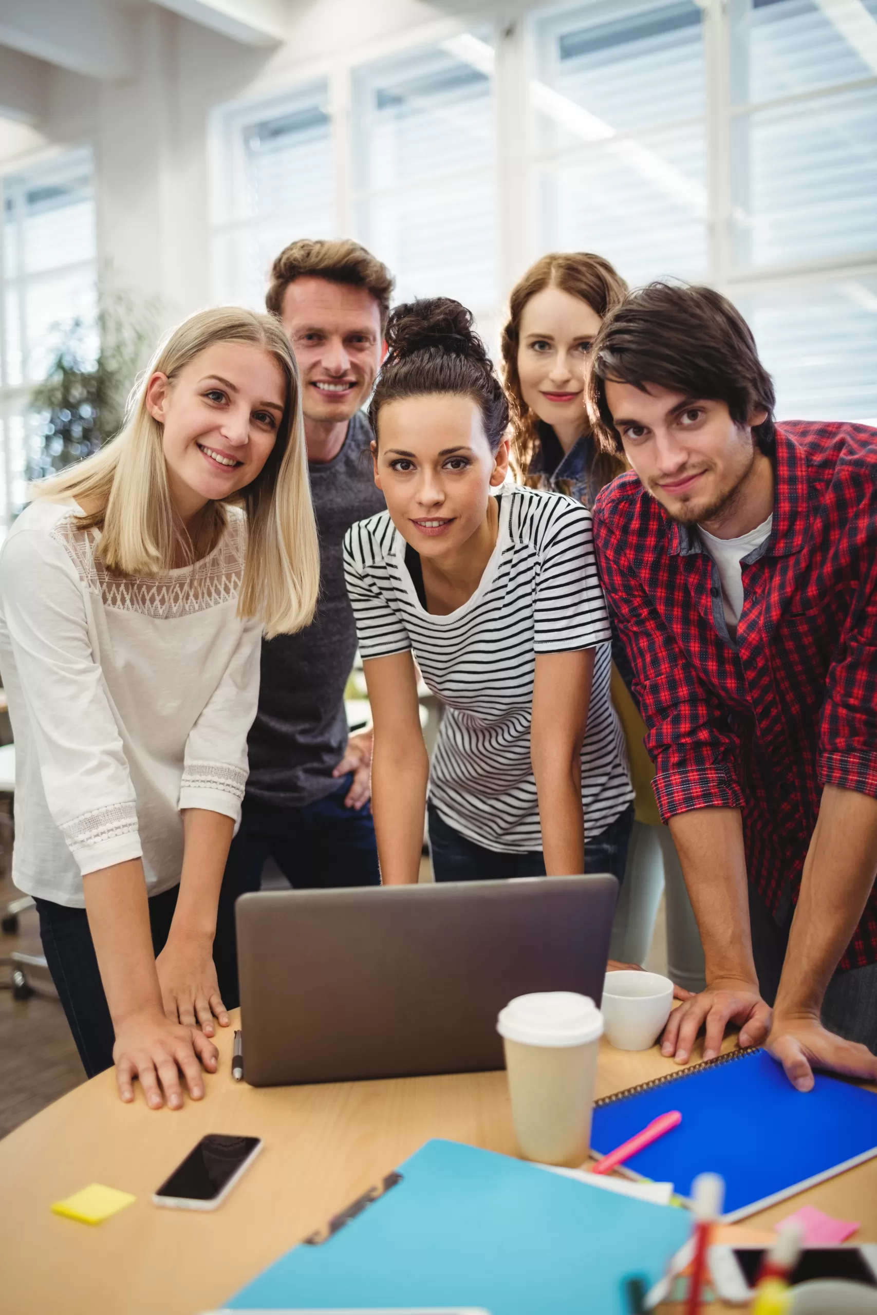 Group of business executives smiling at camera at their desk in the office
